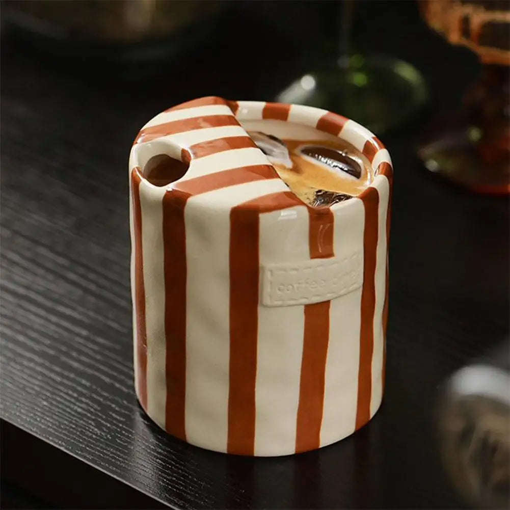 Cylindrical ceramic container with dark orange and white striped pattern on a dark surface