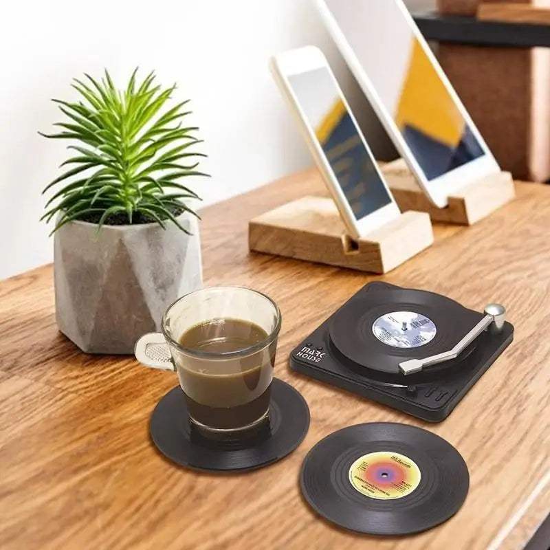 Vinyl record coasters on a wooden table with a cup of coffee and a plant.