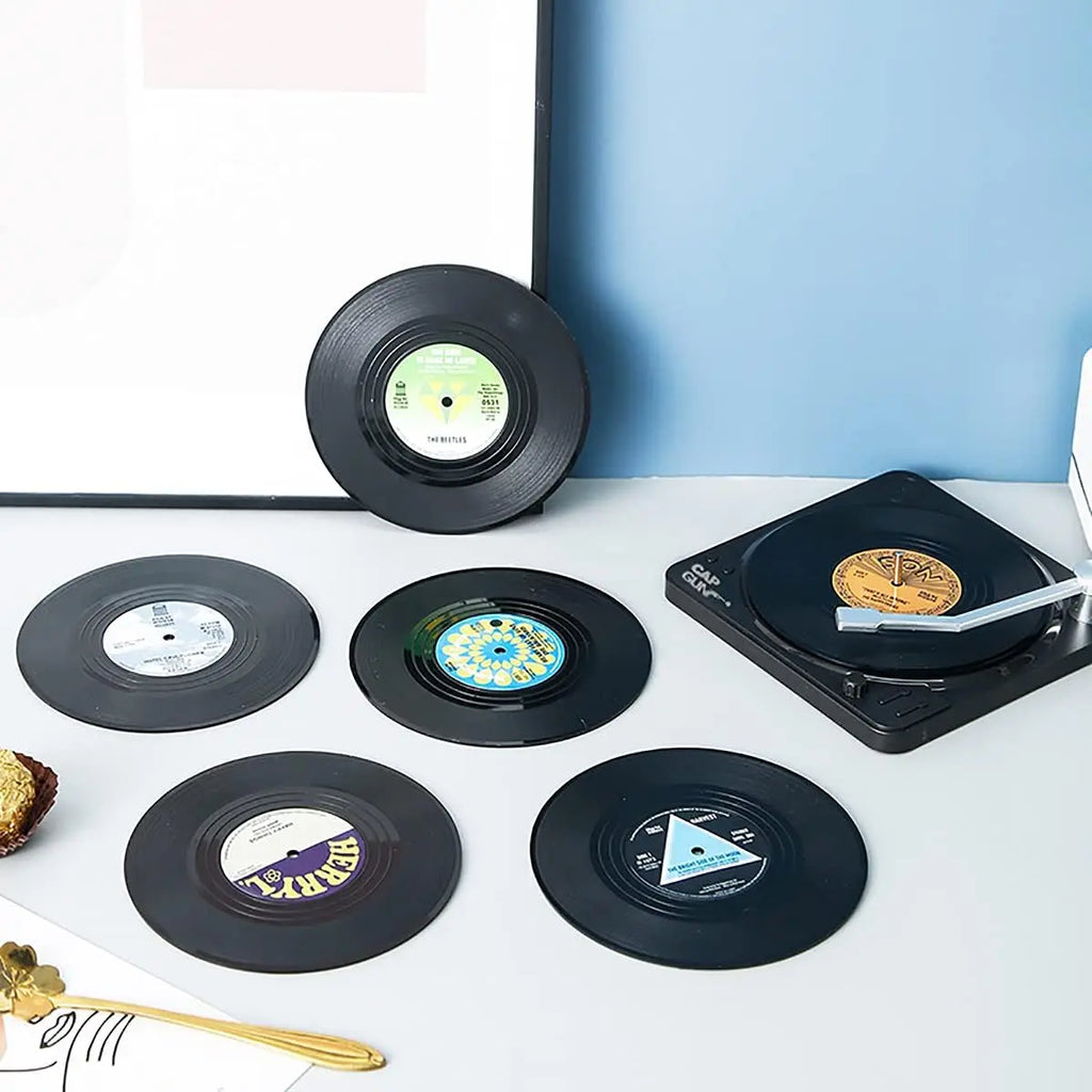 Vinyl records with unique labels on a white surface next to a record player.